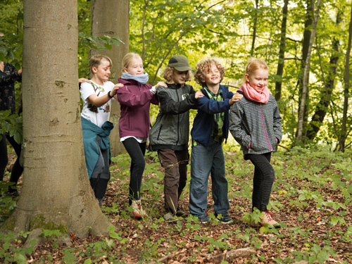 Kinder laufen mit geschlossenen Augen als Raupe durch den Wald