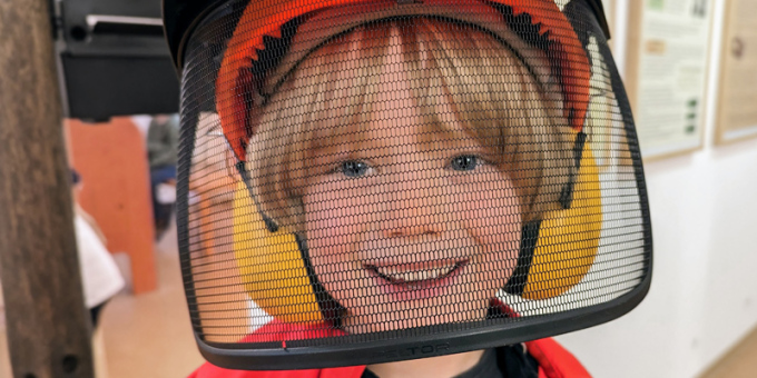 Kind hat Helm mit Visier und Gehörschutz auf