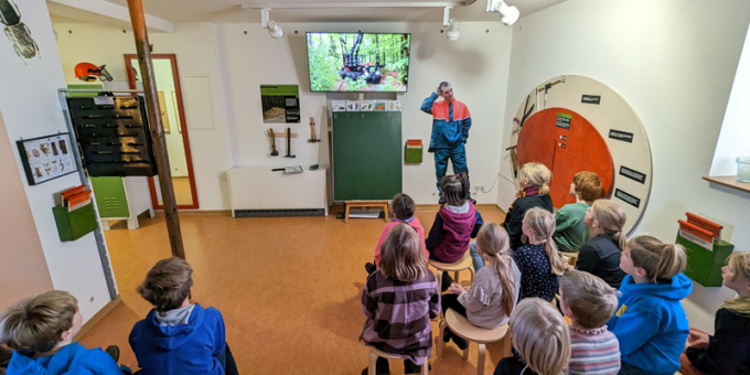 Kinder sitzen vor einem Bildschirm und sehen einen Film