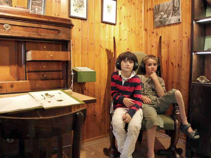 2 Kinder sitzen auf altem Sessel und hören Geschichten