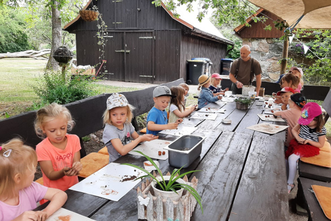 Kinder basteln draußen am Tisch mit Naturmaterialien