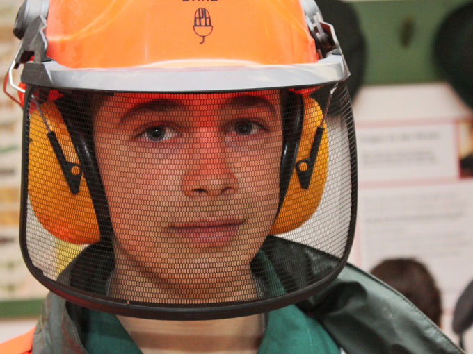 ein Junge trägt Helm mit Gehörschutz und Visier