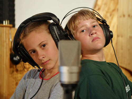 2 Mädchen mit Kopfhörern posieren am Mikrofon